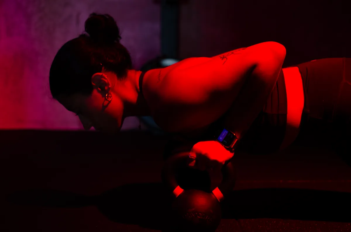 Eli doing a push-up on a kettlebell under red light